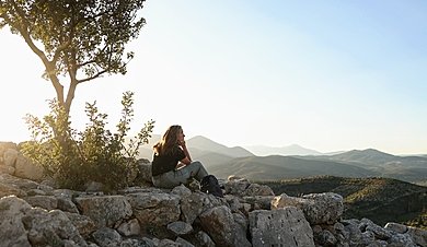  Woman sitting on mountain top 